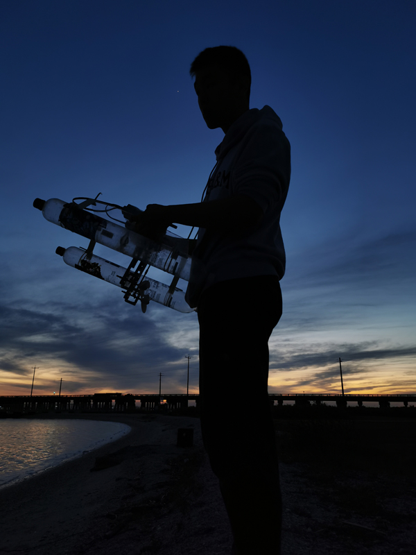 A student standing outside at dawn