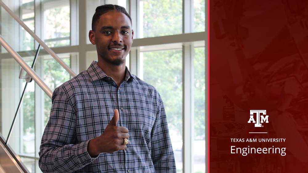 Male student smiles at camera, giving the camera a thumbs up